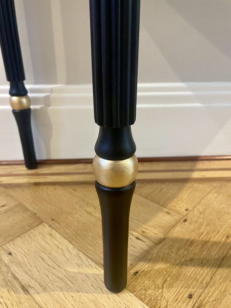 Gold detailing at the foot of a fluted leg