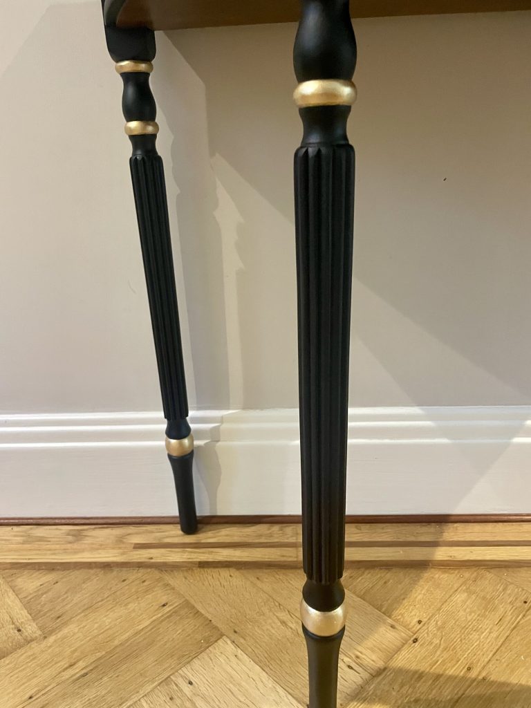 The fluted legs of the Demi-Lune Console with hand-painted gold accents
